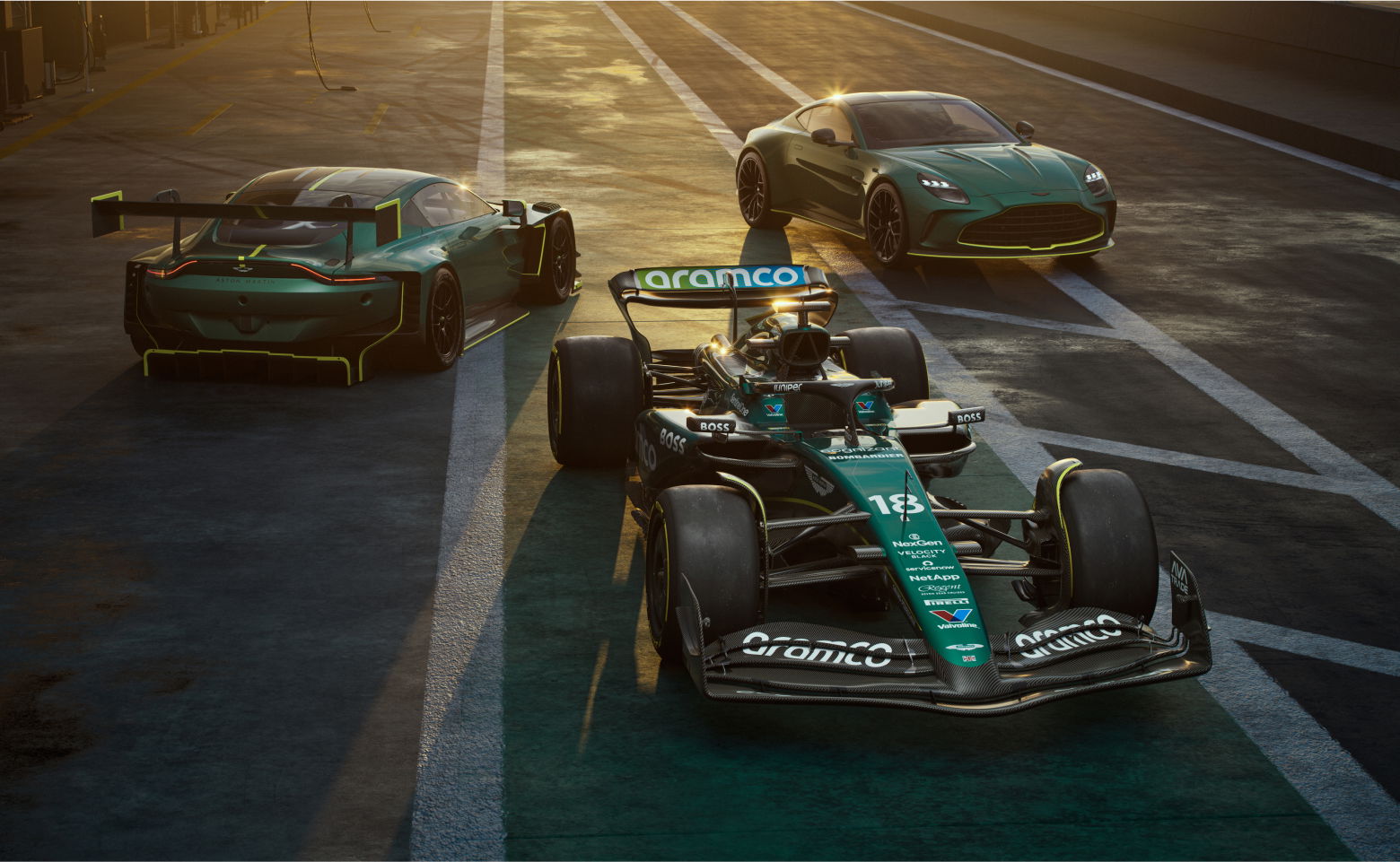 Sports cars parked on a race track at sunset.