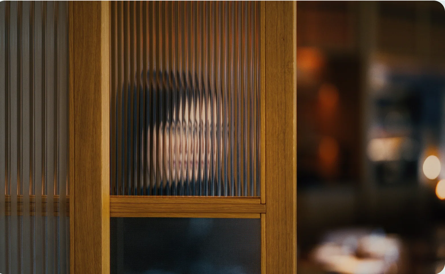 Blurred portrait of woman behind textured glass panel