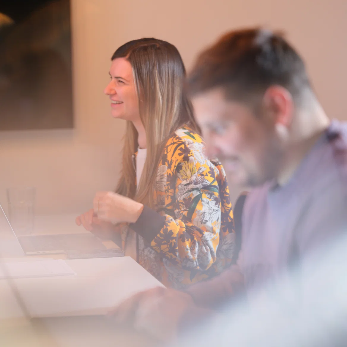 Two colleagues collaborating in a modern office setting with warm lighting.