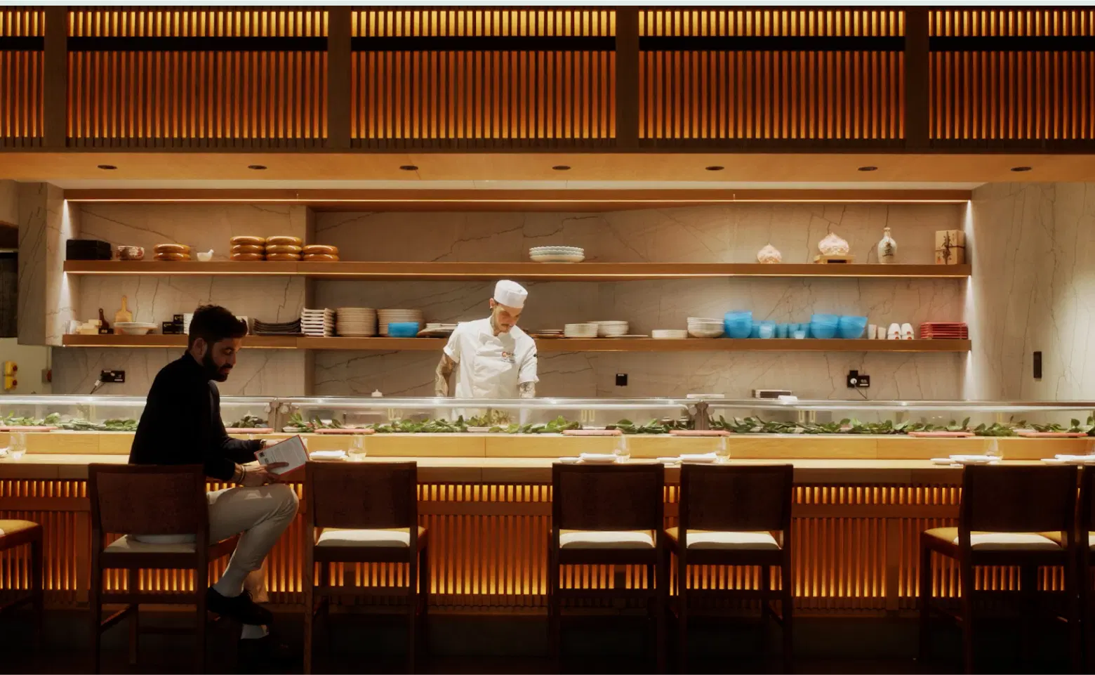 Chef preparing sushi at illuminated restaurant counte