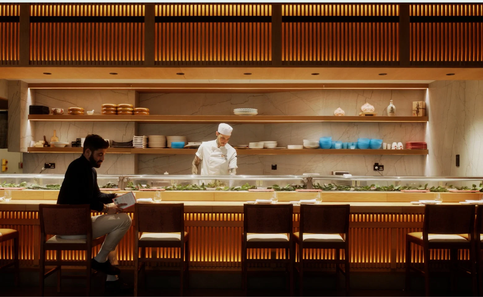 Chef preparing sushi at illuminated restaurant counte