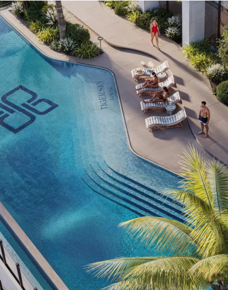 Aerial view of Tiger Sky Tower swimming pool with guests relaxing on sun loungers.