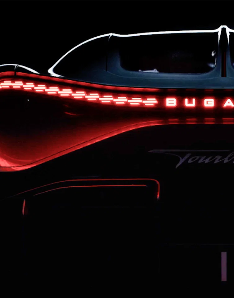 Bugatti rear light strip glowing with red logo illumination.