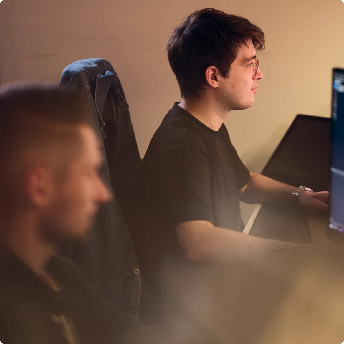Two men working at computers in a warmly lit office environment.