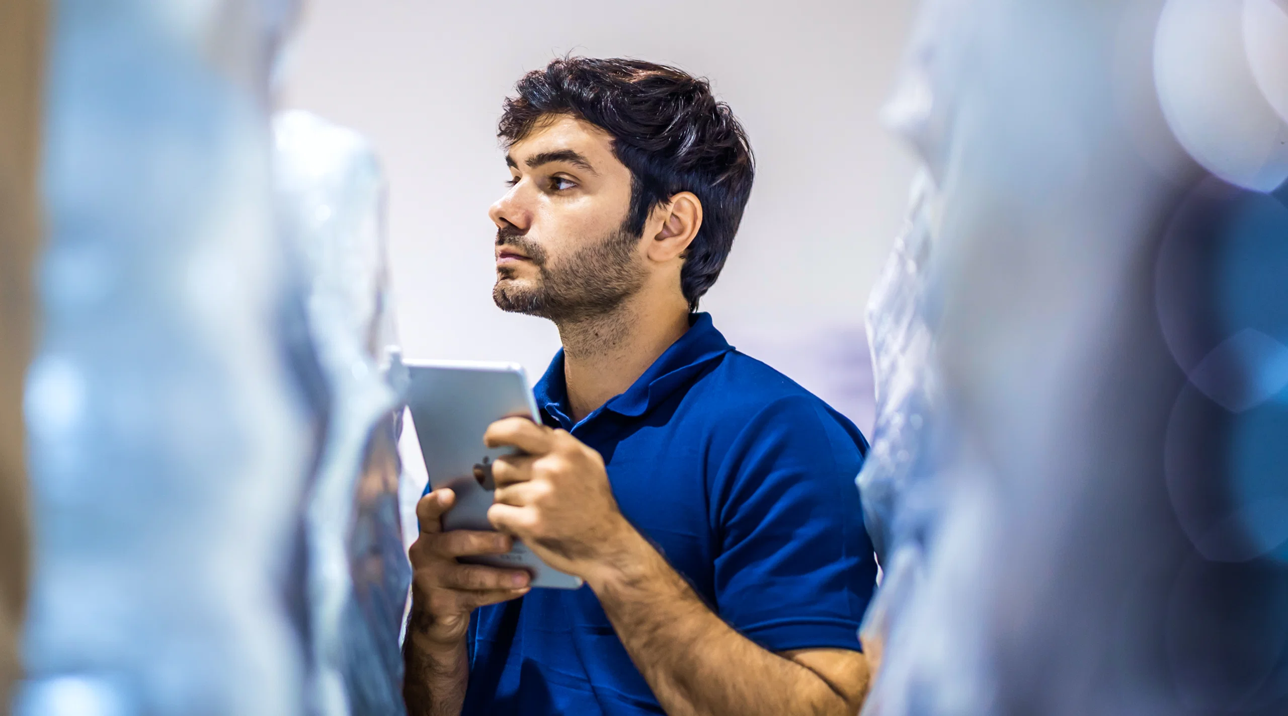 Warehouse worker using a tablet to check inventory between storage racks.