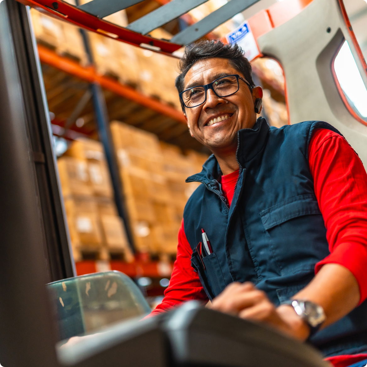Smiling warehouse worker operating machinery in a storage facility.